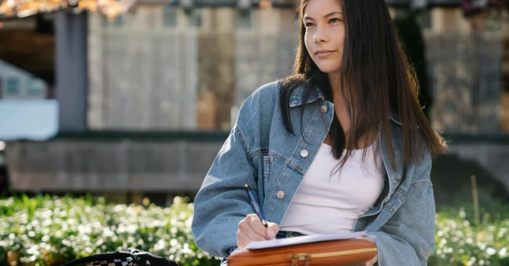 Student in a Blue Denim Jacket Writing Notes