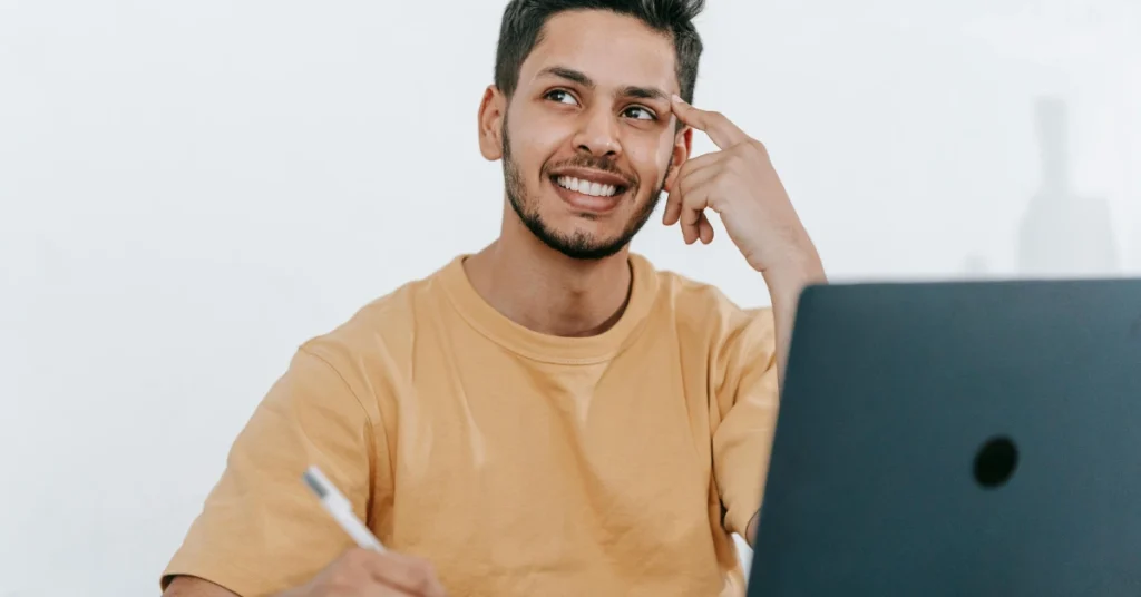 Happy Student Taking Notes Beside Laptop