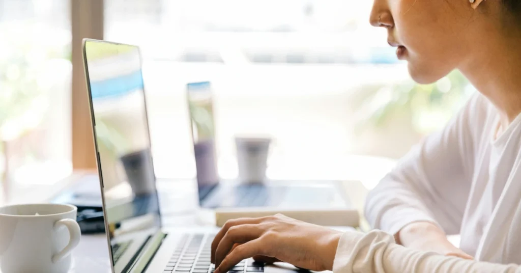 student typing on laptop keyboard in cafe